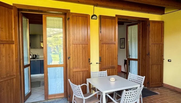 Terrazza con tavolo e sedie di fronte a porte in legno aperte.